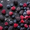 A variety of premium frozen berries including blueberries and raspberries on a dark surface.
